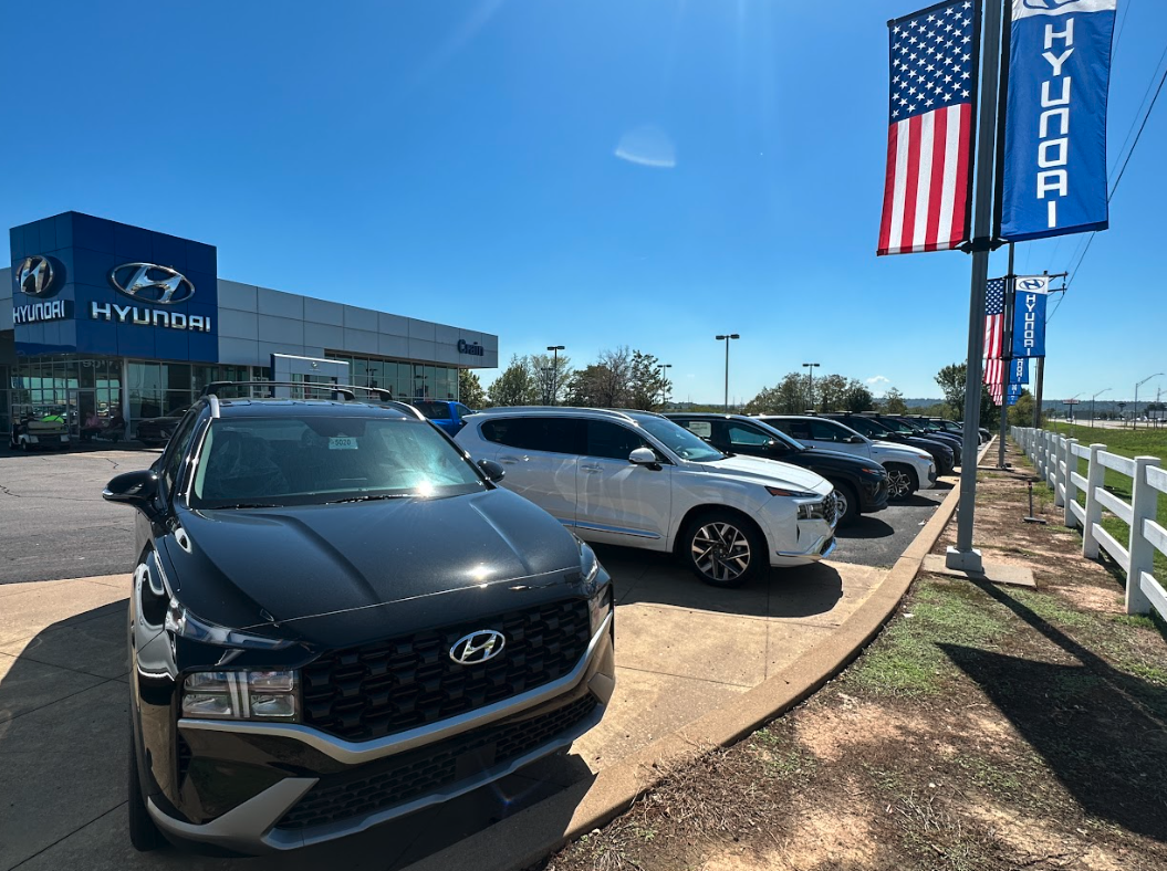 Lineup of Hyundai SUVs at Crain Hyundai dealership under blue sky and American flags